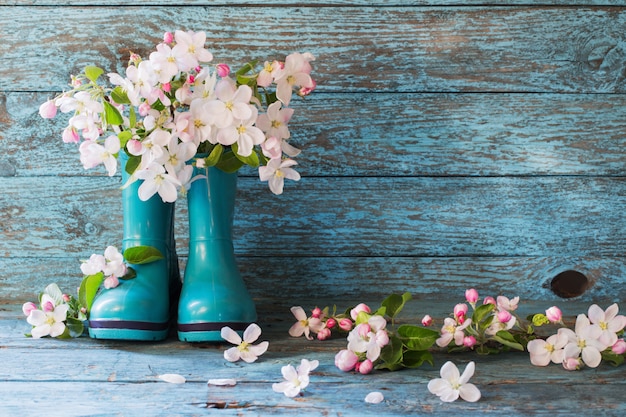 Flores de primavera en botas en mesa de madera