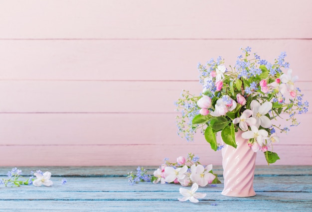 Flores de primavera en florero sobre fondo de madera