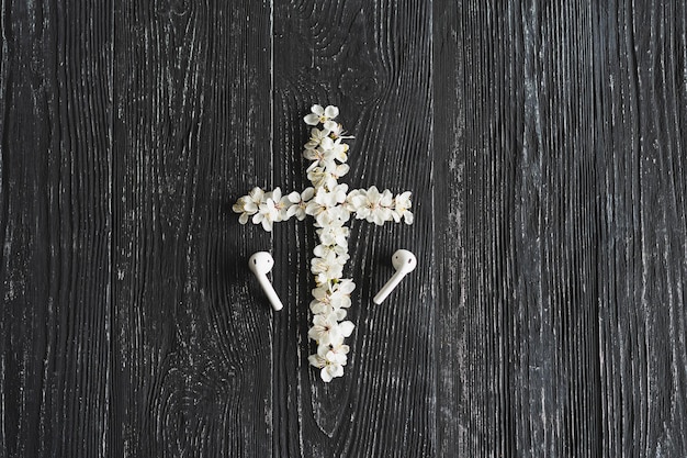Flores de primavera en forma de cruz El concepto de la música cristiana Cruz que simboliza la muerte y resurrección de Jesucristo flores de primavera sobre un fondo de madera