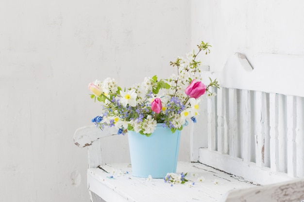 Flores de primavera en interior blanco vintage con banco de madera antiguo