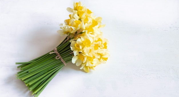 Flores de primavera, narcisos amarillos sobre una mesa de madera clara.