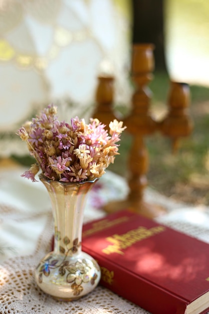 Flores provençais em um vaso no fundo de um castiçal e um livro