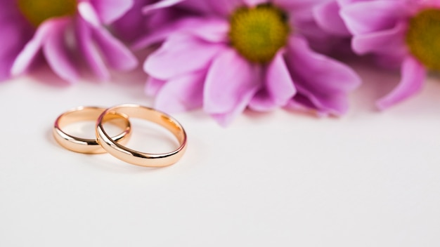 Foto flores púrpuras al lado de los anillos de compromiso