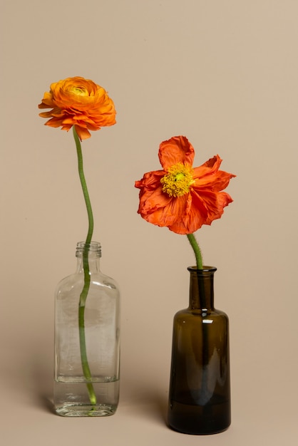 Flores de ranúnculo naranja en flor en un jarrón de botella