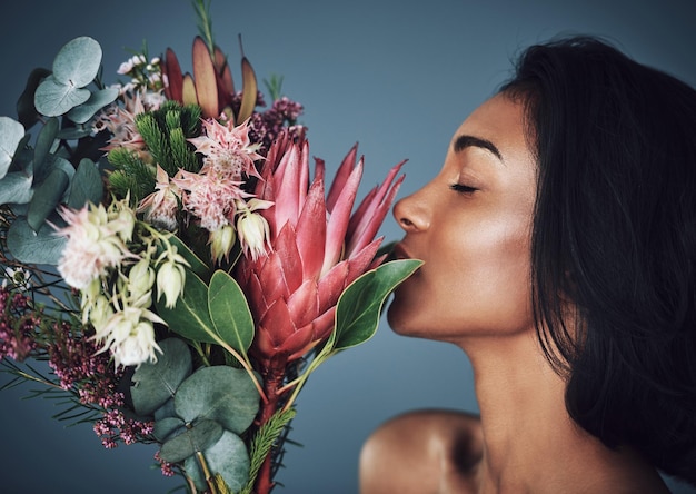 Las flores reflejan quiénes somos Captura recortada de una hermosa joven que huele un ramo de flores