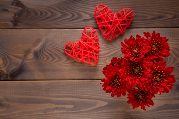 Flores rojas y corazones sobre tabla de madera. Fondo del día de San Valentín Concepto de tarjeta del día de San Valentín