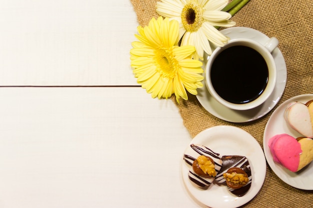 Flores românticas com café e doces na mesa