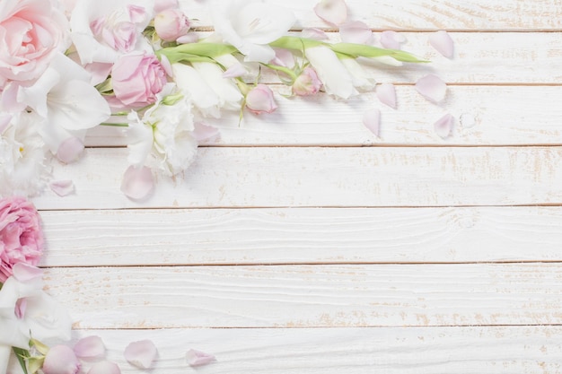 Flores rosadas y blancas sobre fondo blanco de madera