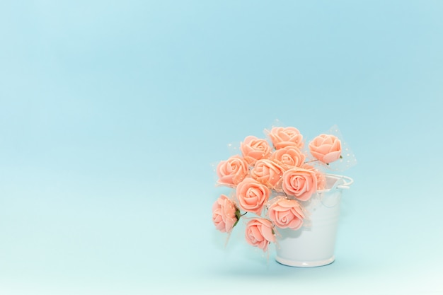 Flores rosadas en un cubo de juguete blanco sobre un fondo azul claro, flores para la fiesta