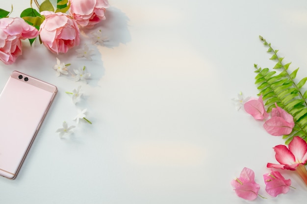 Foto flores rosadas y teléfonos inteligentes sobre fondo blanco.