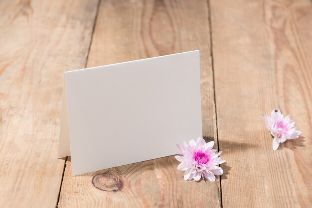 Flores rosas y papel vacío para su texto sobre fondo de madera