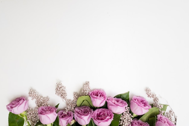 Flores de rosas rosadas en la parte superior de un fondo blanco con adorno de perlas de plata. Elegante telón de fondo del día de la mujer o de la madre.Concepto de Copyspace