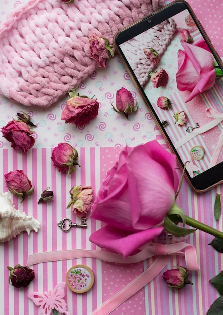 Flores secas e rosa na mesa-de-rosa com smartphone e acessórios fofos