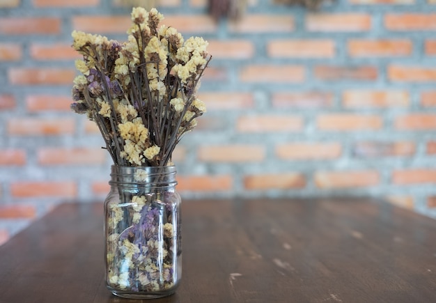 Las flores secas en un jarrón se encuentran en una mesa de madera
