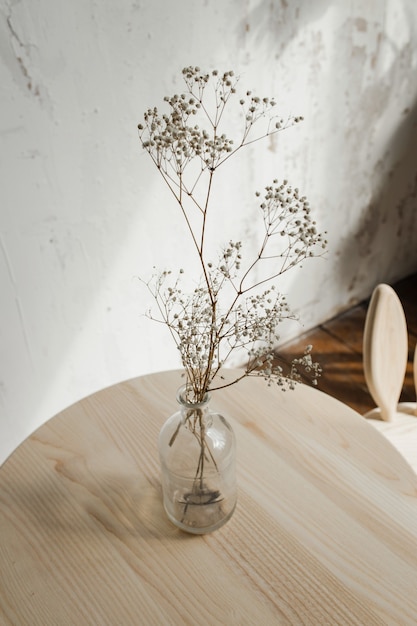 Flores secas en el vaso sobre mesa de madera