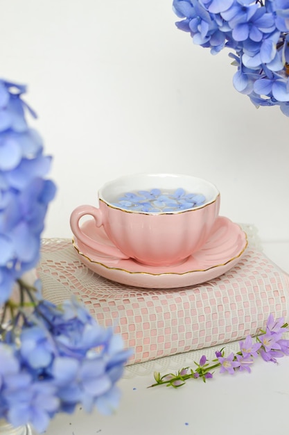 flores silvestres azules en la taza rosa para la hora del té y hermoso fondo