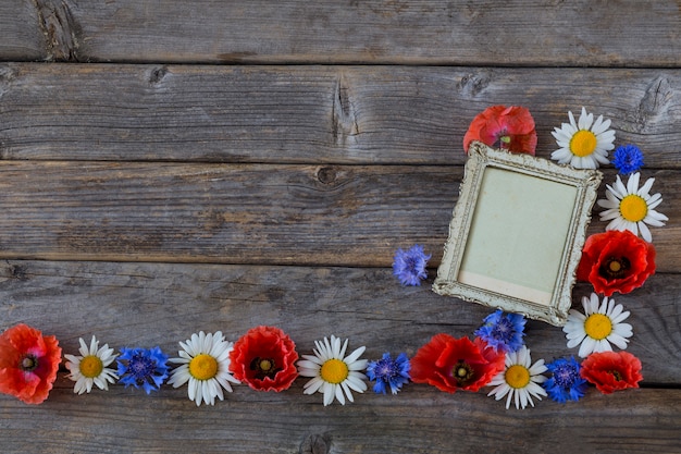 Flores silvestres com moldura vintage na mesa de madeira