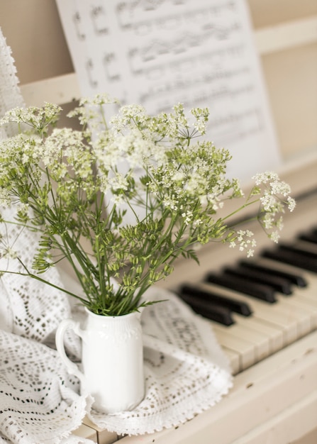 Flores silvestres do ramalhete no piano branco com notas. Foto retrô