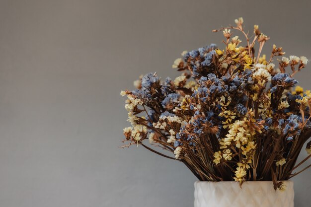 Flores silvestres secas em um vaso branco. Buquê em um fundo cinza.