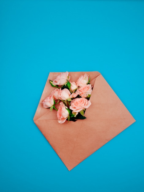 Flores en un sobre de Kraft, copia espacio, fondo azul.