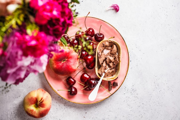 Flores, sobremesa de chocolate e frutas na placa-de-rosa.