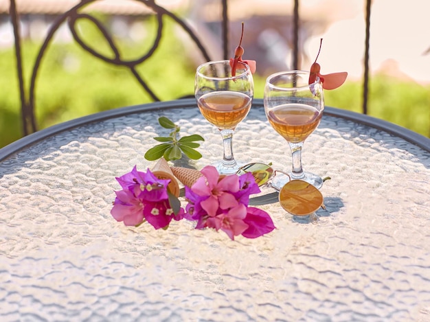 Flores surreais criativas de verão e licor caseiro na mesa de vidro na varanda