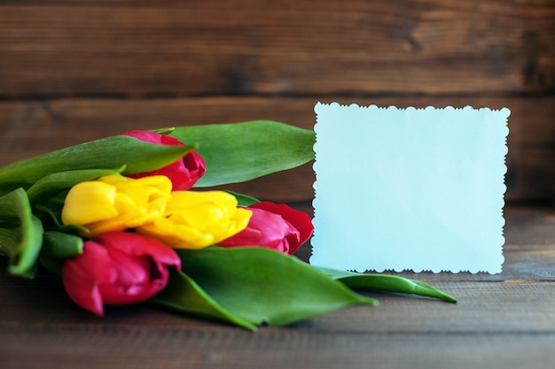 Flores y una tarjeta de bienvenida sobre fondo de madera oscura.