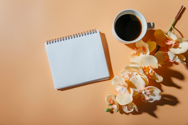 Flores de taza de café y un cuaderno en el fondo