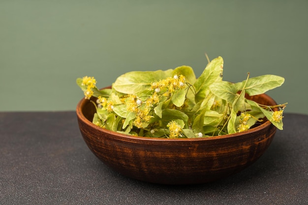 Flores de tilo en un tazón sobre una mesa de madera