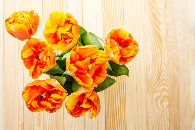 Flores de tulipán naranja sobre una mesa de madera