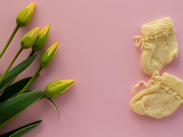 Flores de tulipanes y botines para un recién nacido en el fondo con espacio para copiar