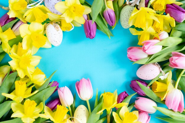 Flores de tulipanes y narcisos con marco de huevos aislado