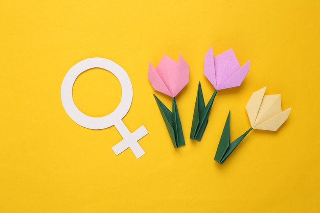 Flores de tulipanes de origami hechas a mano y símbolo de venus sobre fondo amarillo Concepto del día de la mujer