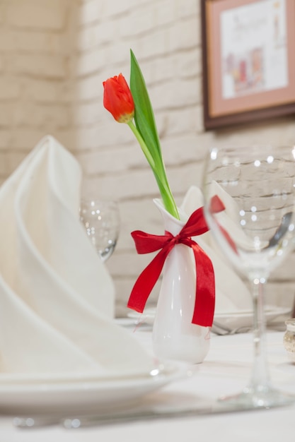 Flores tulipanes rojos en un jarrón sobre una mesa de celebración sobre un fondo claro