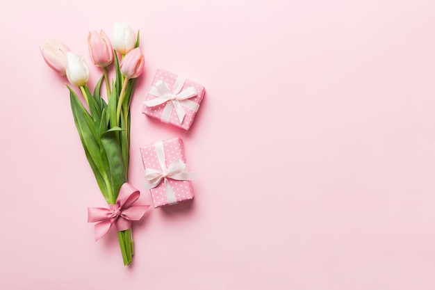 Flores de tulipanes rosados y caja de regalos o regalos en fondo de mesa de colores Día de la Madre, cumpleaños, concepto de celebración del Día de la Mujer Espacio para el texto vista superior