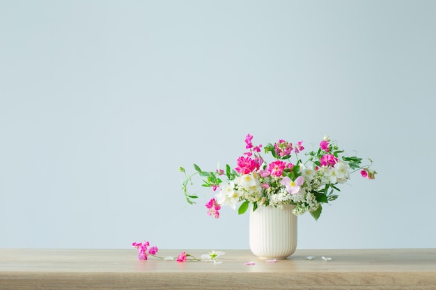 Flores de verano en taza de cerámica sobre fondo claro
