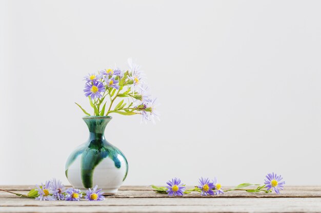 Flores violetas en florero sobre mesa de madera