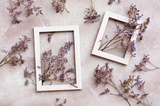 Flores violetas secas en dos marcos de madera blancos y junto a ellas sobre un fondo texturizado. Tarjeta vintage de felicitación romántica. Vista superior