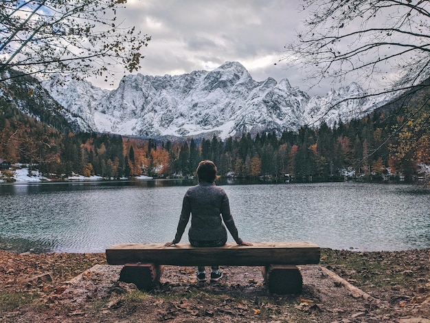 Floresta de Alpes de outono. pinheiros coloridos. Mulher viajante admira a beleza das águas calmas do lago italiano