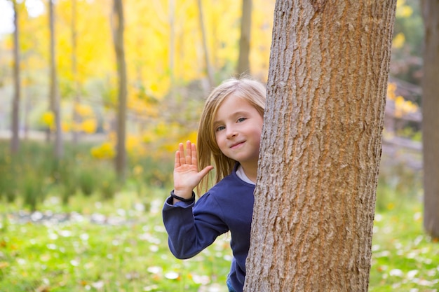 Floresta de Outono com criança menina saudação mão no tronco de árvore