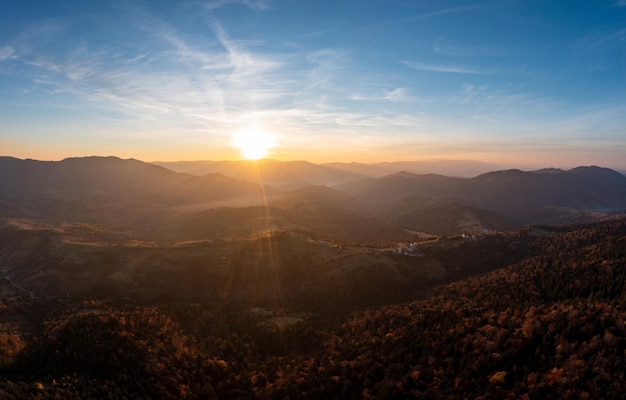 Floresta no cume da montanha sob céu nublado ao pôr do sol brilhante