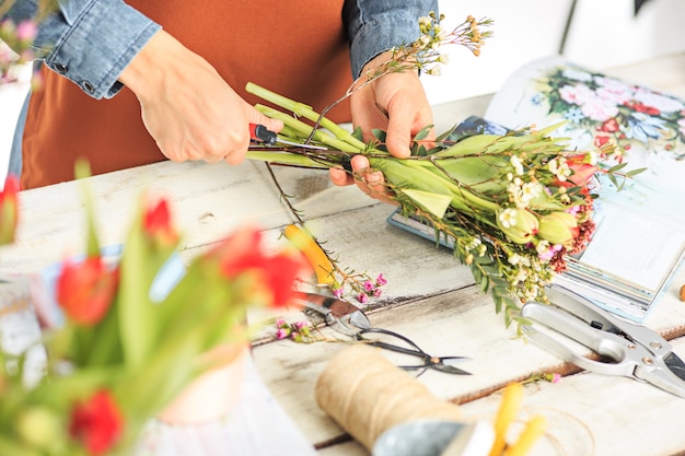 Florist bei der Arbeit: Die weiblichen Hände der Frau, die einen modernen Blumenstrauß aus verschiedenen Blumen herstellen