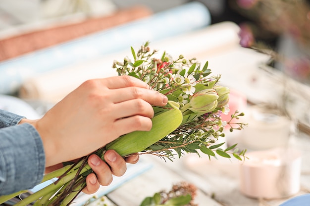 Florist bei der Arbeit: Die weiblichen Hände der Frau, die einen modernen Blumenstrauß aus verschiedenen Blumen herstellen