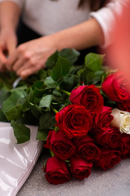 Florist bei der Arbeit Nahaufnahme weibliche Hände schneiden Rosen Frau, die einen Strauß roter Rosen für den Valentinstag macht Frische Rosen für die Blumenstraußlieferung