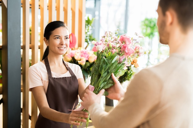 Florist, der dem Käufer Blumenstrauß gibt