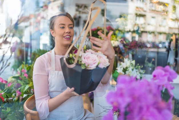 Florist, der ein Schutzblech trägt und Blumen im Blumenladen glücklich vorbereitet