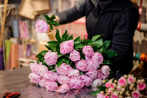 Florist, der einen Blumenstrauß von den rosa Pfingstrosen macht