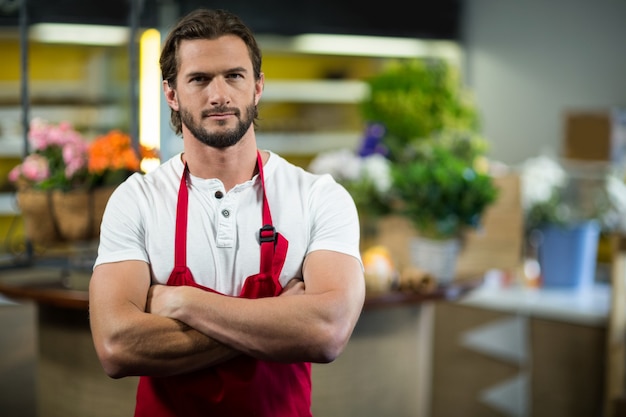 Florist, der im Blumengeschäft mit verschränkten Armen steht