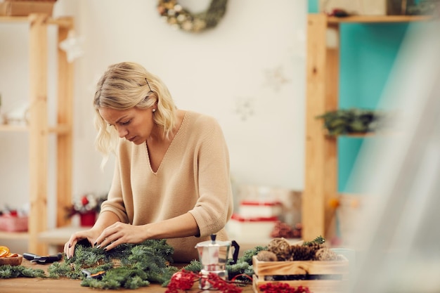 Florist klebt kleine Tannenzweige an den Kranz