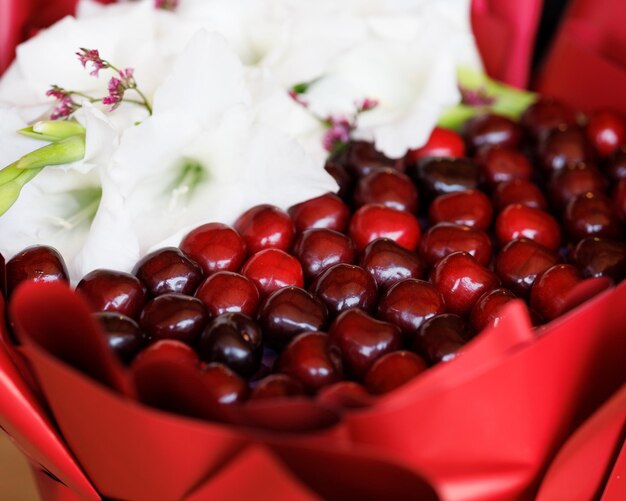 El florista de alimentos recolectó un ramo comestible de flores y bayas de cerezas.